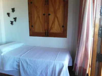 a bedroom with a bed and a wooden cabinet at Bonito Chalet Con Vistas in Sanlúcar de Barrameda