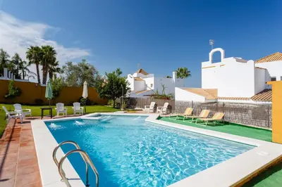 a pool with chairs and a house in the background at Bonito Chalet Con Vistas in Sanlúcar de Barrameda
