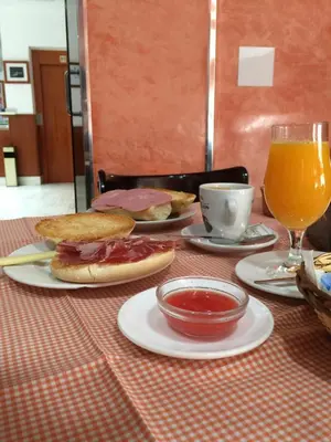a table with plates of sandwiches and a glass of orange juice at Hotel La Parrita in Rota