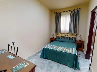 a bedroom with a bed with a green bedspread at Hotel La Parrita in Rota