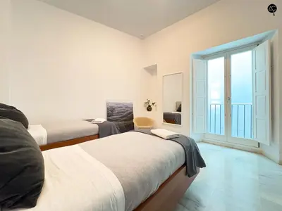 a bedroom with two beds and a window at Casa Columela Cádiz Grupo AC Gestión in Cádiz