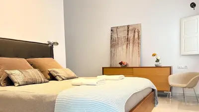 a bedroom with a bed and a chair and a painting at Casa Columela Cádiz Grupo AC Gestión in Cádiz