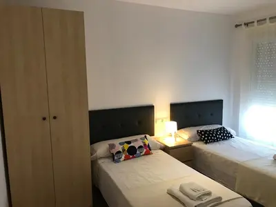 a small bedroom with two beds and a lamp at Piso Aurora in Sanlúcar de Barrameda