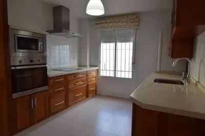 a large kitchen with wooden cabinets and a sink at Piso Aurora in Sanlúcar de Barrameda