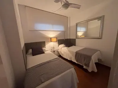 a hotel room with two beds and a mirror at Apartamento La Mar de Cerca. Terraza vistas Mar. 1ª Linea Playa in Cádiz