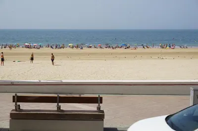 a bench on a beach with a crowd of people at Apartamento La Mar de Cerca. Terraza vistas Mar. 1ª Linea Playa in Cádiz