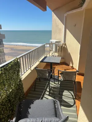 a balcony with chairs and a table and the beach at Apartamento La Mar de Cerca. Terraza vistas Mar. 1ª Linea Playa in Cádiz