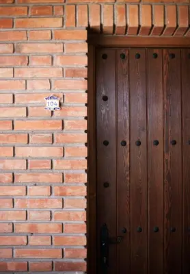 a wooden door in a brick wall with a sign on it at Hospedería Santiago in Chiclana de la Frontera