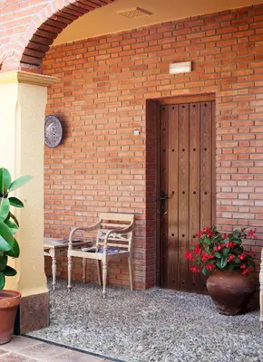 a patio with a bench and a wooden door at Hospedería Santiago in Chiclana de la Frontera