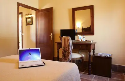 a hotel room with a laptop on a bed with a desk at Hospedería Santiago in Chiclana de la Frontera