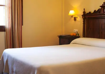 a bedroom with two beds and a table with a lamp at Hospedería Santiago in Chiclana de la Frontera