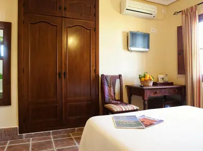 a room with a bed and a cabinet and a table at Hospedería Santiago in Chiclana de la Frontera