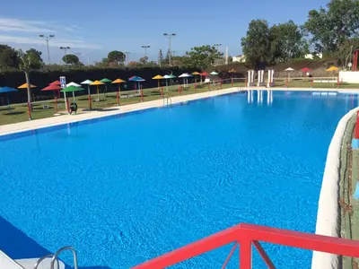 a large blue swimming pool with umbrellas at TAIGA Puerto Santa María in El Puerto de Santa María