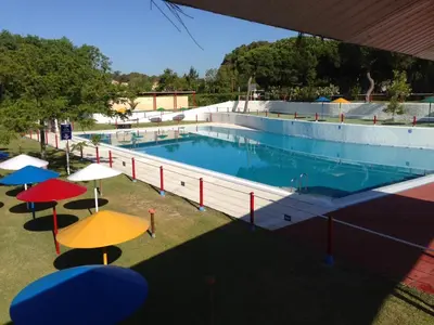 a large swimming pool with umbrellas on the grass at TAIGA Puerto Santa María in El Puerto de Santa María