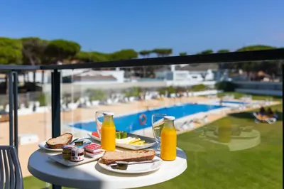 a table with food and drinks and a view of a pool at Complejo Al Sur - by Grupo Tribu in Chiclana de la Frontera