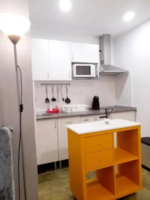 a small kitchen with white cabinets and a yellow island at Estudio Carmen in Cádiz