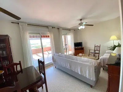 a living room with a couch and a bed and a table at ÁTICO TERRAZA 65m. Playa, piscina, A/C, Wifi in Sanlúcar de Barrameda