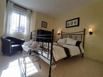 a bedroom with a black bed and a chair at ÁTICO TERRAZA 65m. Playa, piscina, A/C, Wifi in Sanlúcar de Barrameda
