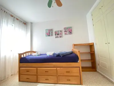 a bedroom with a bed with a blue blanket on it at ÁTICO TERRAZA 65m. Playa, piscina, A/C, Wifi in Sanlúcar de Barrameda
