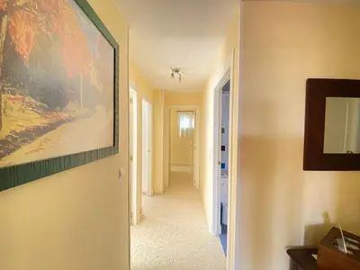a hallway with a painting hanging on a wall at ÁTICO TERRAZA 65m. Playa, piscina, A/C, Wifi in Sanlúcar de Barrameda