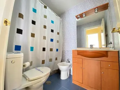 a bathroom with a toilet and a sink and a mirror at ÁTICO TERRAZA 65m. Playa, piscina, A/C, Wifi in Sanlúcar de Barrameda