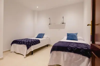 a bedroom with two beds with blue and white sheets at Apartamento El Patio de Canovas in Cádiz