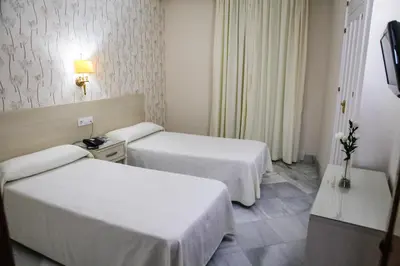 a hotel room with two beds and a television at Chaikana in El Puerto de Santa María