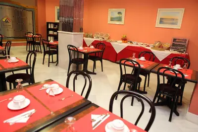 a restaurant with red tables and chairs in a room at Chaikana in El Puerto de Santa María
