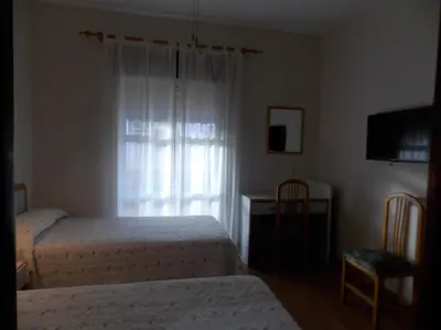 a bedroom with two beds and a desk and a window at Pensión La Palma in El Puerto de Santa María