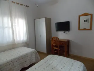 a small bedroom with two beds and a television at Pensión La Palma in El Puerto de Santa María