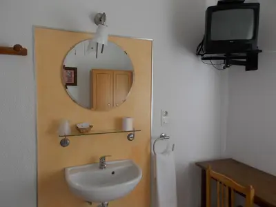 a bathroom with a sink and a mirror and a tv at Pensión La Palma in El Puerto de Santa María