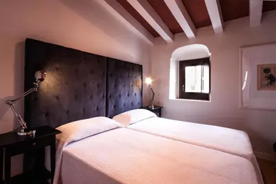a bedroom with a large white bed with a black headboard at Palacio Torneria in Jerez de la Frontera