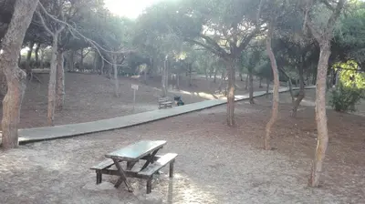 a picnic table and bench in a park with a walkway at Casa Blanca in Rota