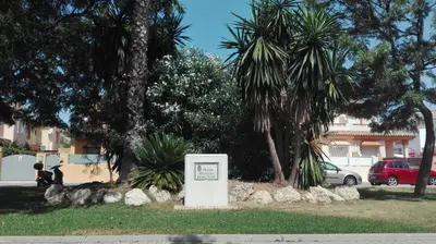 a sign in a park with palm trees and a building at Casa Blanca in Rota