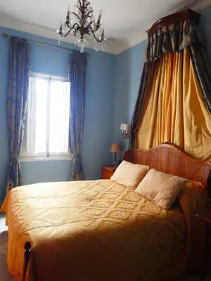 a bedroom with a bed with blue walls and a chandelier at Palacio del Virrey Laserna in Jerez de la Frontera