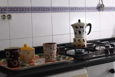 a stove with three coffee mugs on a tray at Apartamento Tres Carretas Puerto Real in Puerto Real