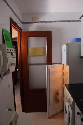 a small kitchen with a refrigerator and a door at Apartamento Tres Carretas Puerto Real in Puerto Real