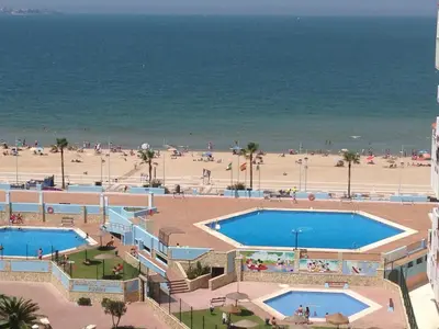 a view of a beach with two pools and the ocean at Piso frente la playa de Valdelagrana in El Puerto de Santa María