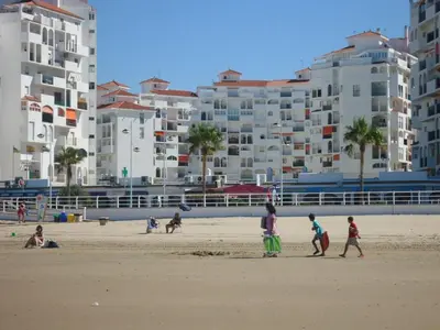 a group of people walking on a beach with buildings at Piso frente la playa de Valdelagrana in El Puerto de Santa María