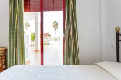a bedroom with a bed and a view of a patio at Bonito apartamento en campo de golf con piscina in Sanlúcar de Barrameda