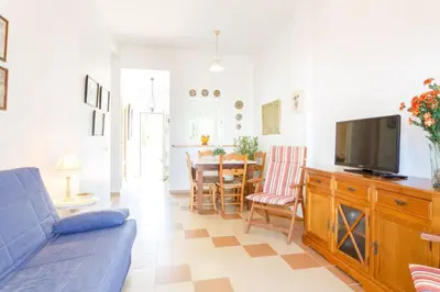 a living room with a blue couch and a tv at Bonito apartamento en campo de golf con piscina in Sanlúcar de Barrameda