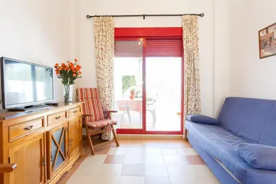 a living room with a blue couch and a tv at Bonito apartamento en campo de golf con piscina in Sanlúcar de Barrameda