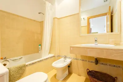 a bathroom with a toilet and a sink and a tub at Bonito apartamento en campo de golf con piscina in Sanlúcar de Barrameda
