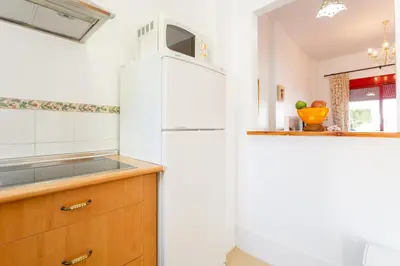 a white refrigerator in a kitchen with a counter at Bonito apartamento en campo de golf con piscina in Sanlúcar de Barrameda