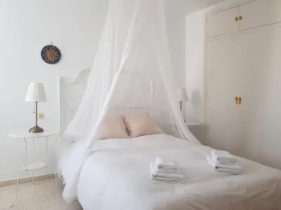 a white bedroom with a white bed with a mosquito net at Valdelagrana Mar Ha Apartment in El Puerto de Santa María