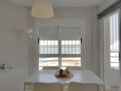 a white dining room table with chairs and a window at Valdelagrana Mar Ha Apartment in El Puerto de Santa María