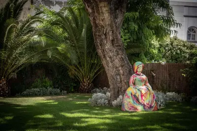 a statue of a woman sitting in the grass next to a tree at Hotel Casa Palacio María Luisa in Jerez de la Frontera
