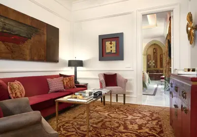 a living room with a red couch and two chairs at Hotel Casa Palacio María Luisa in Jerez de la Frontera