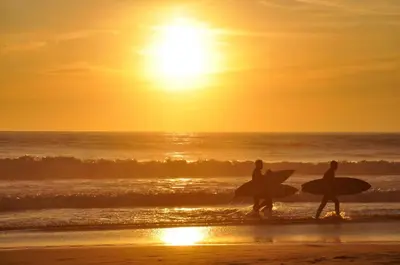 two people walking on the beach with their surfboards at Modern design apartament in Conil! in Conil de la Frontera