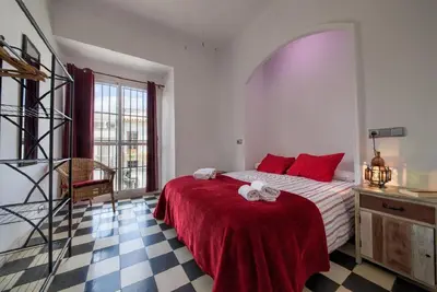 a bedroom with a bed with red pillows on it at Apartamentos Jerez in Jerez de la Frontera